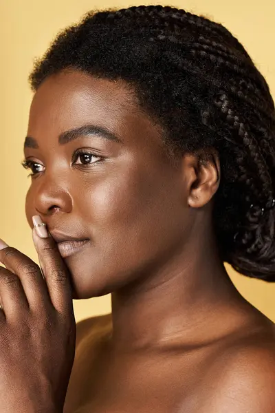 A young african american woman showcases her radiant skin in a bright studio. — Stock Photo