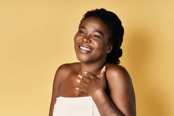 A young African American woman radiates confidence with her glowing skin in a studio environment. — Stock Photo