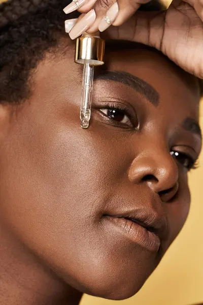 Young Black woman showcases confidence and beauty using an oil serum for skin care. — Stock Photo