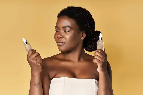 Young woman displays skincare products with confidence in a lively studio ambiance. — Stock Photo