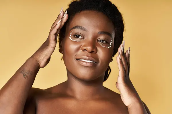 A young African American woman showcases her radiant skin in a professional studio. — Stock Photo