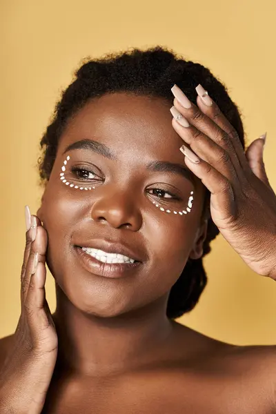 Young woman with beautiful skin highlights her skincare routine in a warm studio setting. — Stock Photo