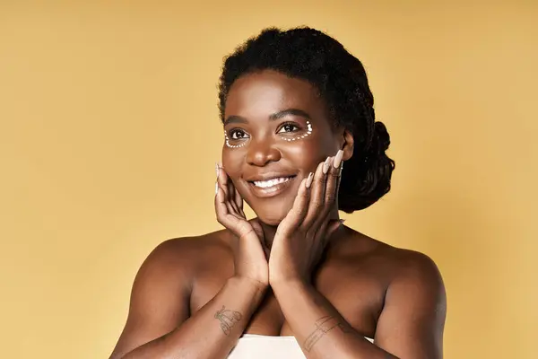 A young Black woman exudes confidence and radiance while caring for her skin in a studio. — Stock Photo