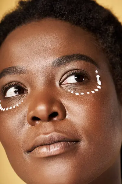 A young African American woman showcases her beautiful skin while focusing on skincare in a studio. — Stock Photo