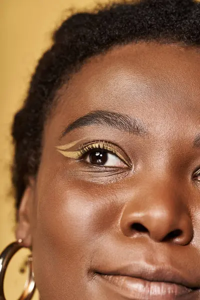 In a lively studio, a young Black woman showcases her beautiful skin and artistic makeup. — Stock Photo