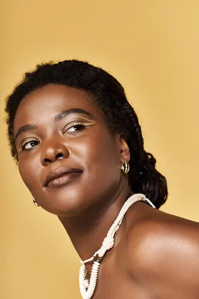Young Black woman highlights her beauty against a warm yellow backdrop. — Stock Photo