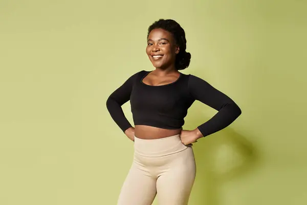Joven deportista afroamericana muestra con confianza su fuerza en un vibrante estudio. - foto de stock