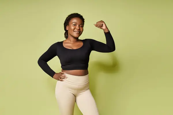 Dedicado joven afroamericana deportista muestra fuerza en un ambiente de estudio brillante. - foto de stock