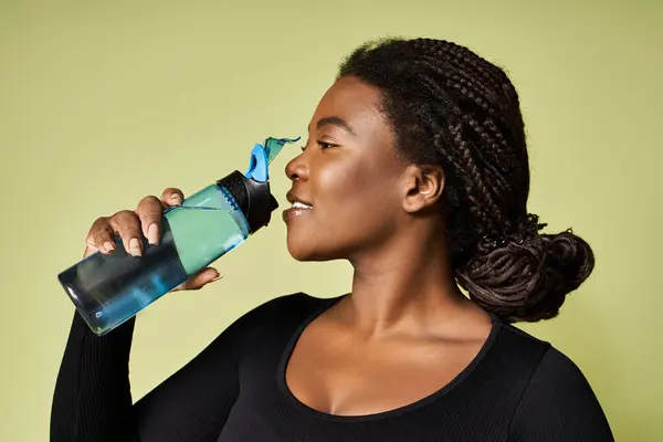 Young fit african american woman drinks water while working out in a vibrant studio. — Stock Photo