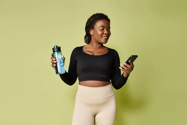 Young fit african american woman balances exercise and technology in an inviting studio. — Stock Photo