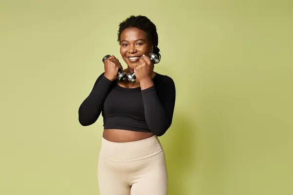 Fit young african american sportswoman engages in weight training in bright studio space. — Stock Photo