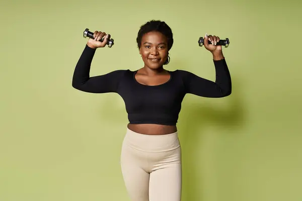 Jovem apto afro-americano esportista levanta pesos com confiança em um estúdio brilhante. — Fotografia de Stock