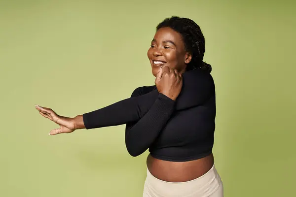 Jeune femme s'engage joyeusement dans une routine d'étirement énergique dans un studio dynamique. — Photo de stock