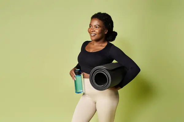 Enfocado joven en forma mujer afroamericana se prepara para un entrenamiento energizante en un estudio brillante. - foto de stock