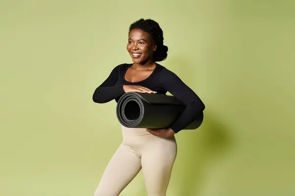 A fit African American woman confidently prepares for her workout while smiling in a lively studio. — Stock Photo