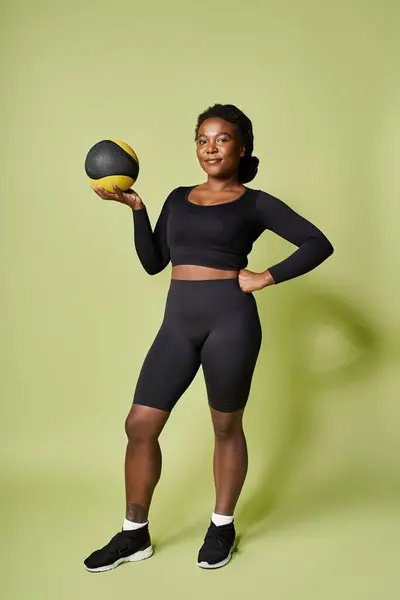 A young fit African American woman is working out with a medicine ball in a studio. — Stock Photo