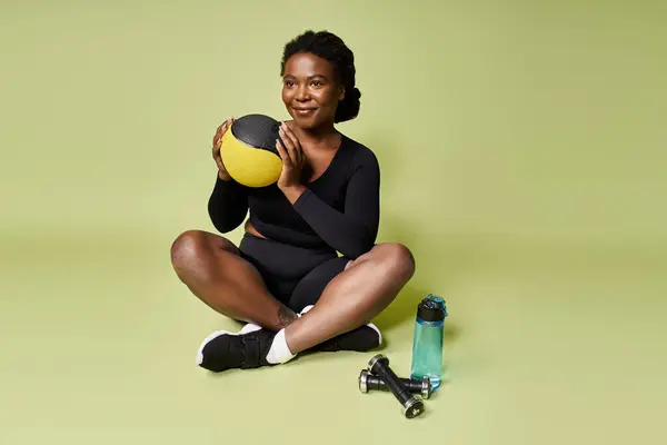 A young fit African American sportswoman is focused on her workout while seated in a lively studio. — Stock Photo
