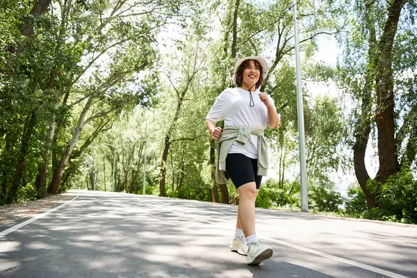 Una giovane donna corre felicemente lungo un sentiero alberato, immersa nella sua routine di allenamento all'aria aperta. — Foto stock