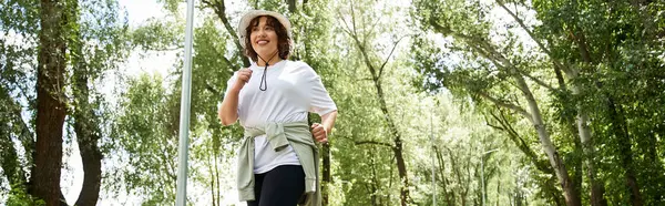 Fit and active woman runs joyfully on a path surrounded by lush greenery during daytime, banner — Stock Photo