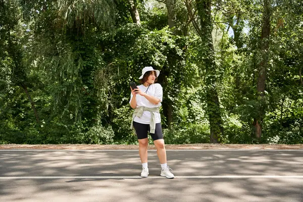 Brightly dressed woman stands on a path in the woods enjoying a sunny summer day outdoors. — Stock Photo