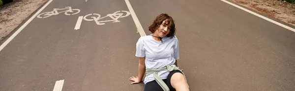 A young woman relaxes outdoors on a quiet cycling path surrounded by greenery, banner — Stock Photo