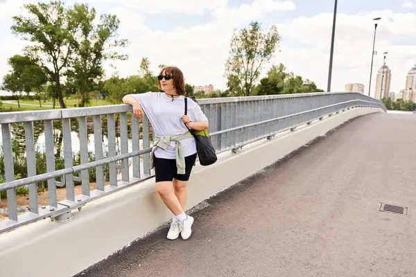 A pretty young woman relaxes after a workout outdoors by the river, soaking in the urban landscape. — Stock Photo