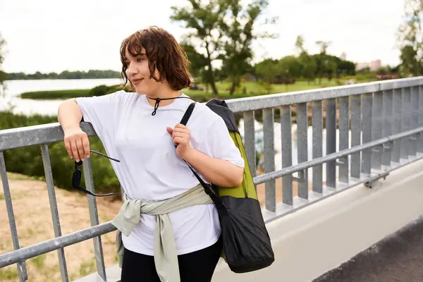 A fit woman exercises by a serene riverside, showcasing her outdoor workout routine and confidence. — Stock Photo