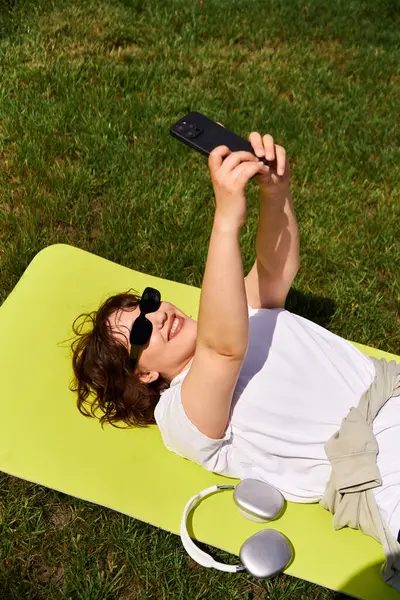 A pretty young woman lies on a bright mat, capturing moments of joy on a summer day outdoors. — Stock Photo