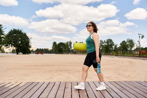 Fit young woman enjoys outdoor workout while confidently walking by the beachside. — Stock Photo
