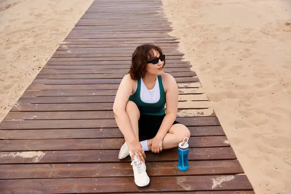 A young woman smiles on the boardwalk, enjoying a moment of relaxation after exercising. — Stock Photo