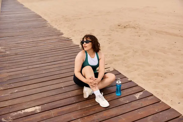 A fit young woman relaxes on a warm deck, enjoying outdoor time after beach exercise. — Stock Photo