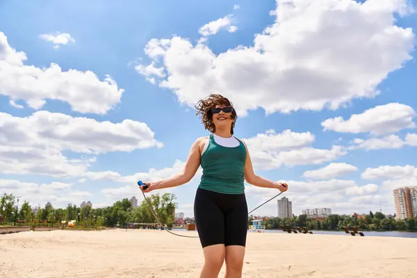 A young woman skips rope joyfully on a warm sunny day, surrounded by nature. — Stock Photo