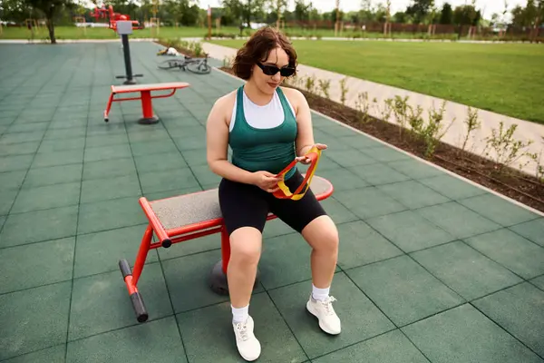 Fitness enthusiast takes a break, enjoying her workout routine on a sunny day in a park. — Stock Photo