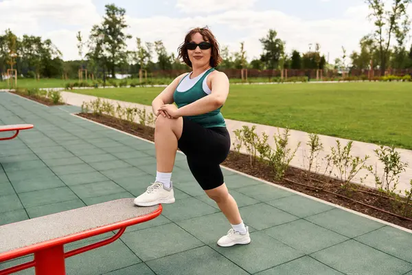 A fit young woman stretches outdoors, enjoying the warm sun and fresh air. — Stock Photo