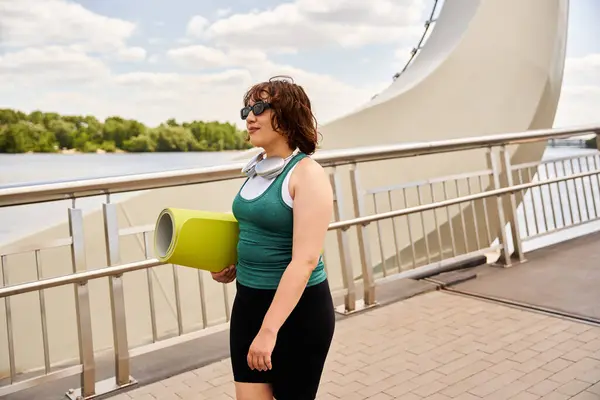 Eine fitte junge Frau geht selbstbewusst den Fluss entlang, bereit für ihre Outdoor-Übung. — Stockfoto