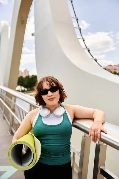 Young woman stretches her arms by the railing, exuding confidence after workout outdoors. — Stock Photo