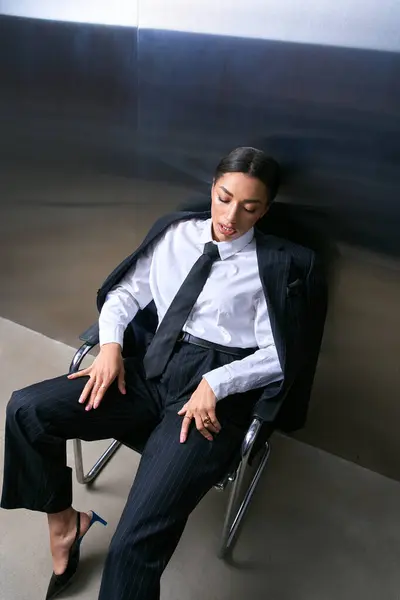 A young woman dressed in sophisticated attire confidently relaxes in a contemporary setting. — Stock Photo