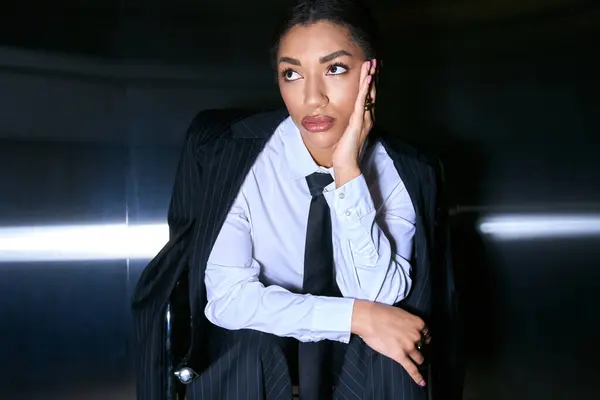Una mujer joven y elegante muestra su sentido de la moda mientras está sentada en un entorno moderno. - foto de stock