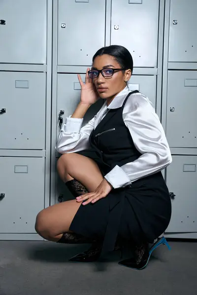 Una joven confiada posa con estilo junto a elegantes casilleros en un entorno moderno. - foto de stock