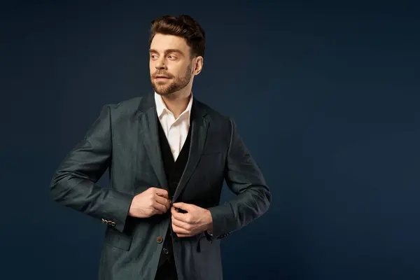 A man adjusts his suit jacket, embodying elegance and joy on dark backdrop. — Stock Photo