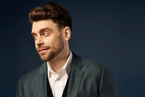 Handsome young man with beard in suit posing on dark backdrop. — Stock Photo
