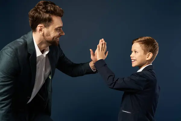 A father and son share a joyful high five, celebrating their bond on Fathers Day 2025. — Stock Photo
