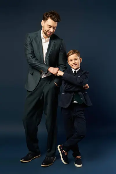 Un padre y un hijo comparten un momento alegre, elegantemente vestidos para una celebración festiva. - foto de stock