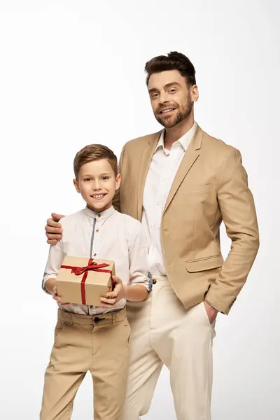 A father and son smile with a gift, celebrating their bond and love. — Stock Photo