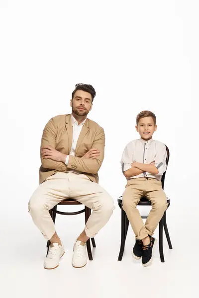 A father and son sit side by side, embracing joy and connection during Fathers Day festivities. — Stock Photo