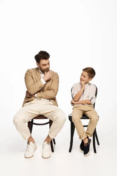 A father and son bond with smiles and thoughtful looks during a festive celebration. — Stock Photo
