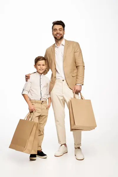 Un padre y un hijo celebran juntos el Día del Padre, sosteniendo con alegría las bolsas de la compra. - foto de stock