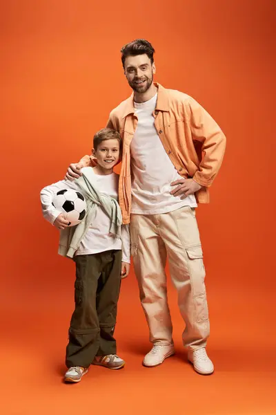 A father and son embrace each other, sharing smiles while holding a soccer ball, radiating joy. — Stock Photo