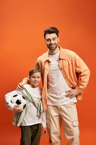 A father and son share a moment of happiness together with a soccer ball, radiating love. — Stock Photo