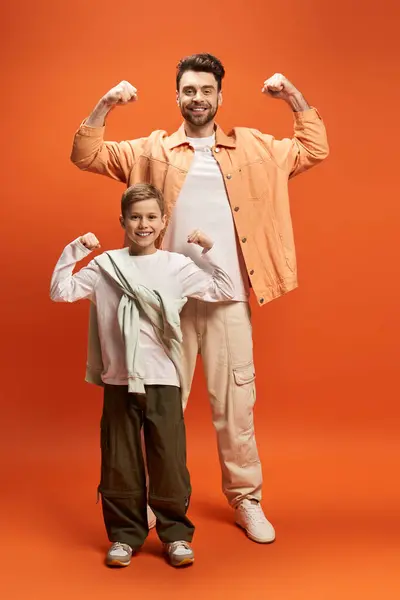 Padre e hijo comparten un momento de orgullo, flexionando sus músculos juntos en un ambiente festivo. - foto de stock